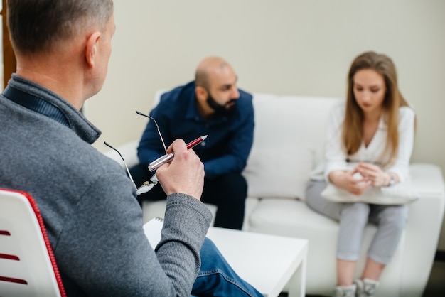 A young married couple of men and women talk to a psychologist\
at a therapy session. psychology.