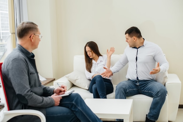 A young married couple of men and women talk to a psychologist at a therapy session. Psychology.