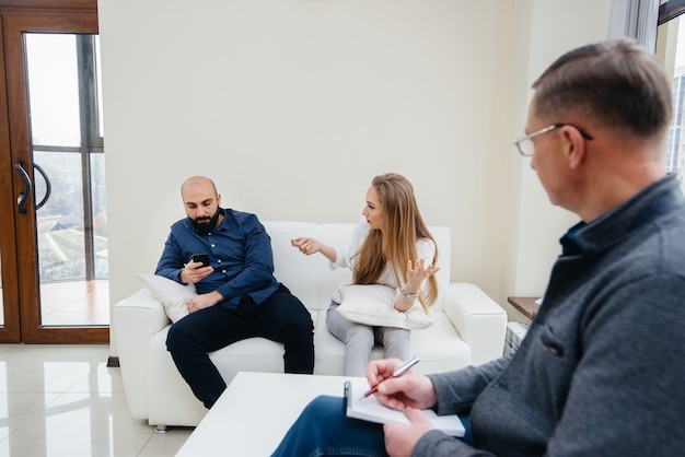 A young married couple of men and women talk to a psychologist at a therapy session