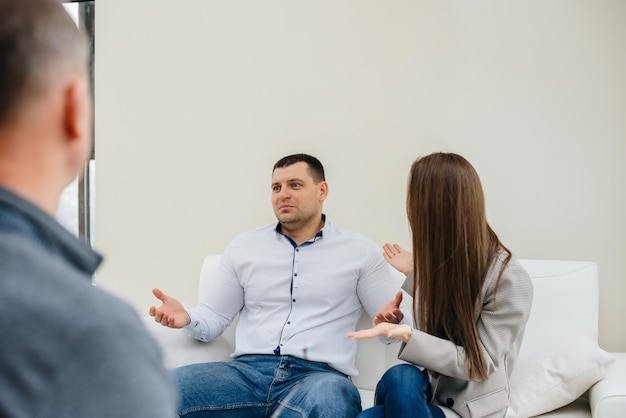 A young married couple of men and women talk to a psychologist at a therapy session