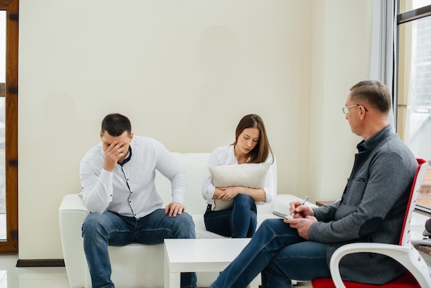 A young married couple of men and women talk to a psychologist\
at a therapy session