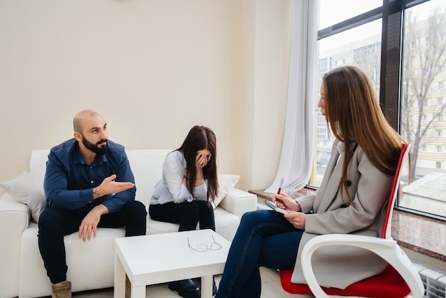 A young married couple of men and women talk to a psychologist at a therapy session