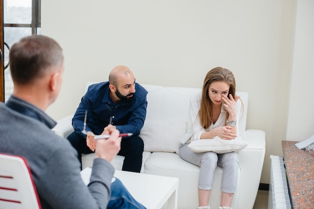 A young married couple of men and women talk to a psychologist at a therapy session