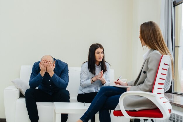 A young married couple of men and women talk to a psychologist\
at a therapy session