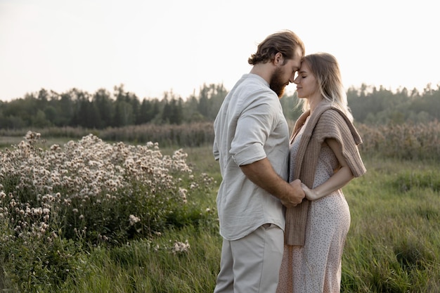 A young married couple walks in beige outfits in the park and hugs in the beautiful sunset light of the sun