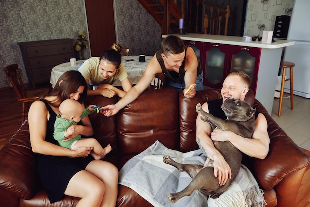 Young married couple with an american bully dog is sitting on sofa in living room while visiting