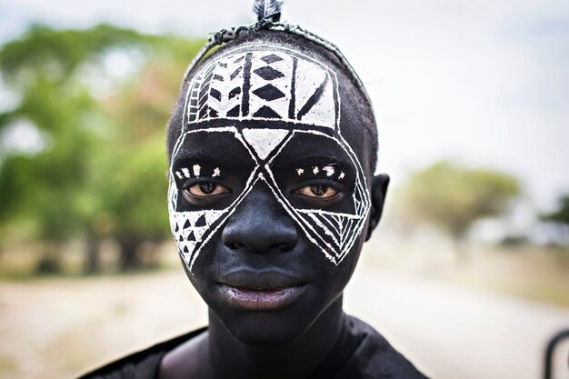 伝統的な黒と白のフェイスペインティングと黒い服を着たマサイ族の若い戦士、アルーシャ