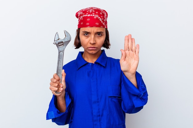 Young mechanical woman holding a key isolated standing with outstretched hand showing stop sign, preventing you.