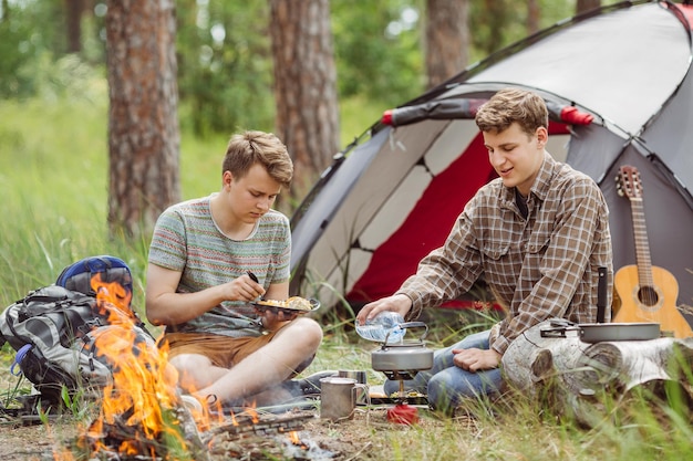 Young men are heated in a fire and cook out on a summer camp