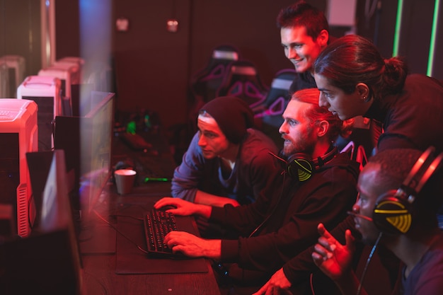 Photo young men assisting friend to pass video game