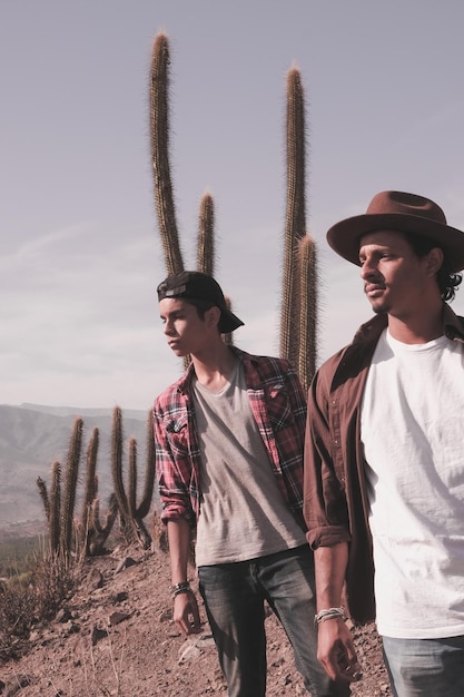 Photo young men looking away while standing against cactus on field