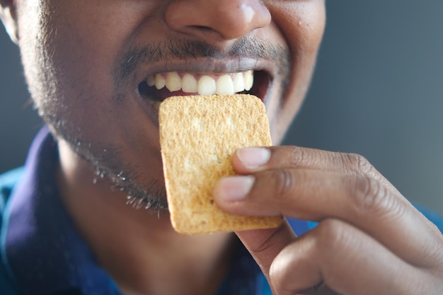 Young men mouth eating a biscuit