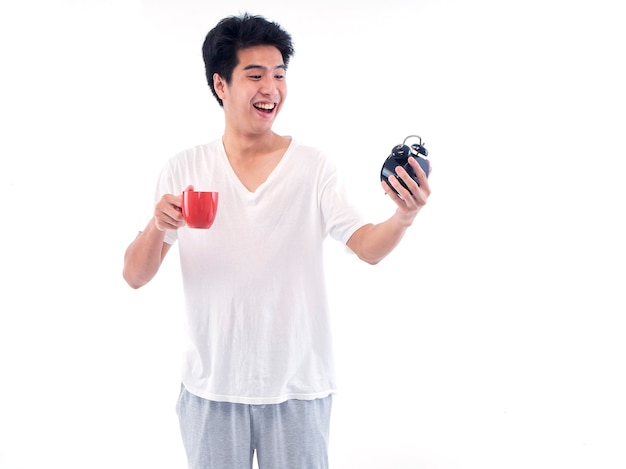 Young men in pajamas holding cup of coffee and alarm clock isolated