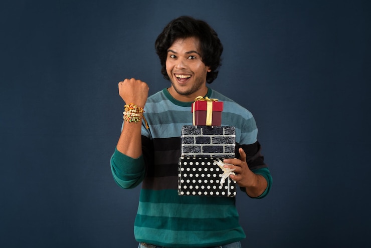 फोटो young men showing rakhi on his hand with gift box on the occasion of raksha bandhan festival