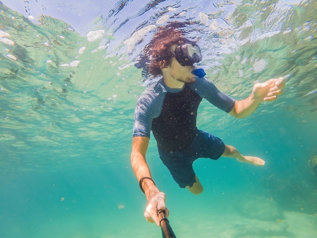 Young men snorkeling exploring underwater coral reef landscape background in the deep blue ocean with colorful fish and marine life