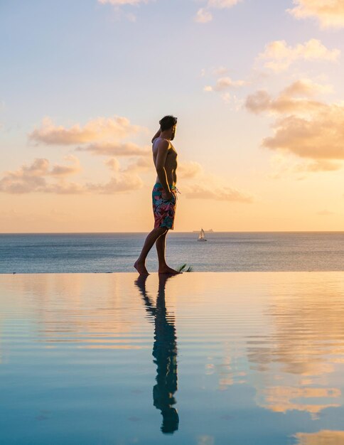 Young men in swim short at saint lucia caribean men at infinity
pool during sunset