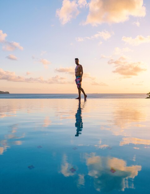 Young men in swim short at saint lucia caribean men at infinity\
pool during sunset