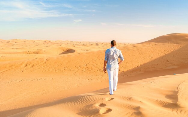 Foto giovani uomini che camminano nel deserto di dubai dune di sabbia di dubai emirati arabi uniti