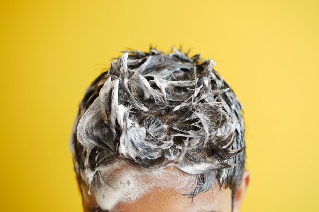 Young men washes h his hair with shampoo