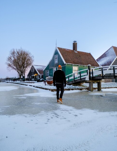 Young men in winter visit the zaanse schans windmill village during winter with snow