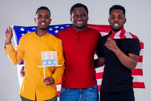 Giovani uomini con bandiera americana su sfondo bianco. amici felici pronti per le vacanze visto americano
