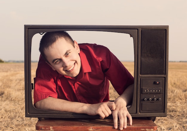 Young men with vintage TV in summer field