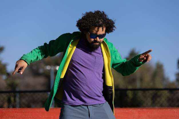 Photo young mexican man with curly hair dancing happily in a park in mexicohappiness and freedom concept