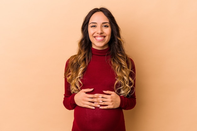 Young mexican pregnant woman isolated on beige happy, smiling and cheerful.