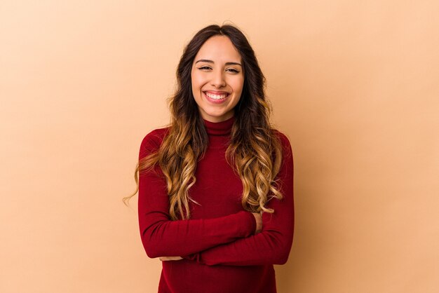 Young mexican pregnant woman isolated on beige wall laughing and having fun.