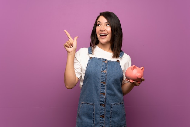 Young Mexican woman   holding a big piggybank