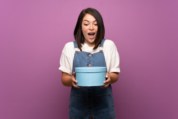 Young Mexican woman over isolated background holding gift box