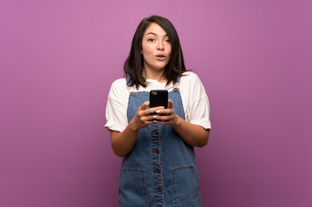 Young Mexican woman over isolated background using mobile phone