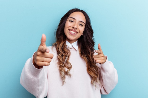 Young mexican woman isolated on blue background cheerful smiles pointing to front.