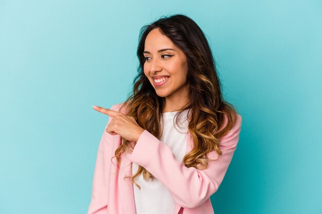 Young mexican woman isolated on blue background looks aside smiling, cheerful and pleasant.