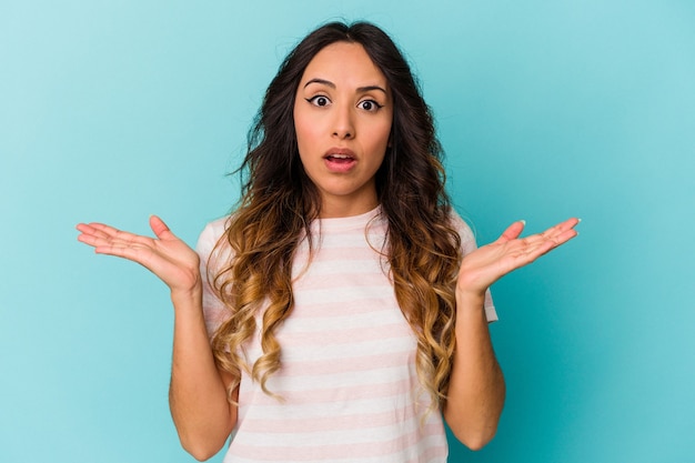 Young mexican woman isolated on blue background surprised and shocked.