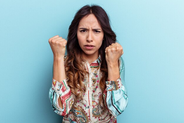 Young mexican woman isolated on blue background upset screaming with tense hands.