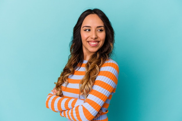 Young mexican woman isolated on blue wall laughing and having fun.