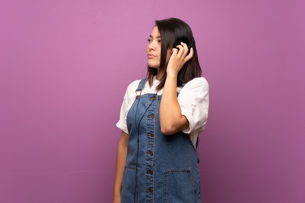 Young Mexican woman over isolated  listening to music with headphones