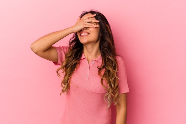 Young mexican woman isolated on pink background covers eyes with hands, smiles broadly waiting for a surprise.