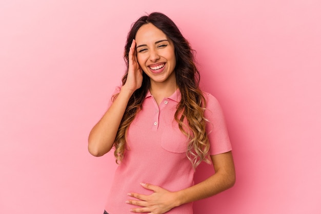 분홍색 배경에 고립 된 젊은 멕시코 여자는 행복 하 게 웃음과 뱃속에 손을 유지하는 재미있다.