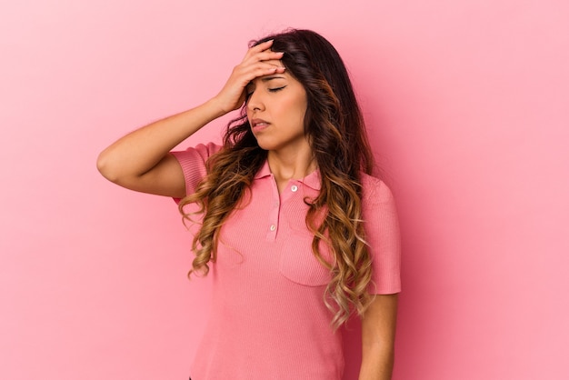 Молодая мексиканская женщина изолирована на розовом фоне, трогательно висков и имея головную боль.