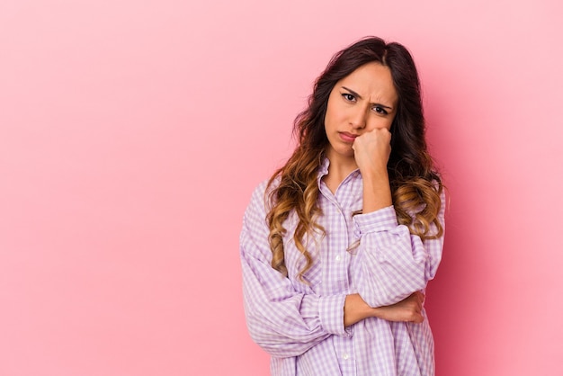 Young mexican woman isolated on pink background who feels sad and pensive, looking at copy space.