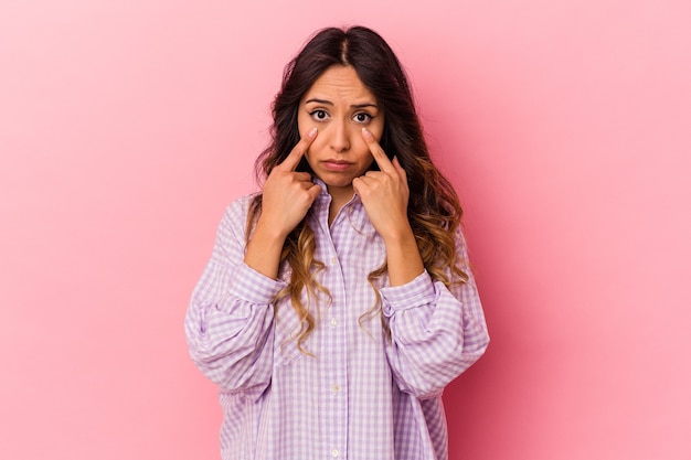 Young mexican woman isolated on pink wall crying, unhappy with something, agony and confusion concept.