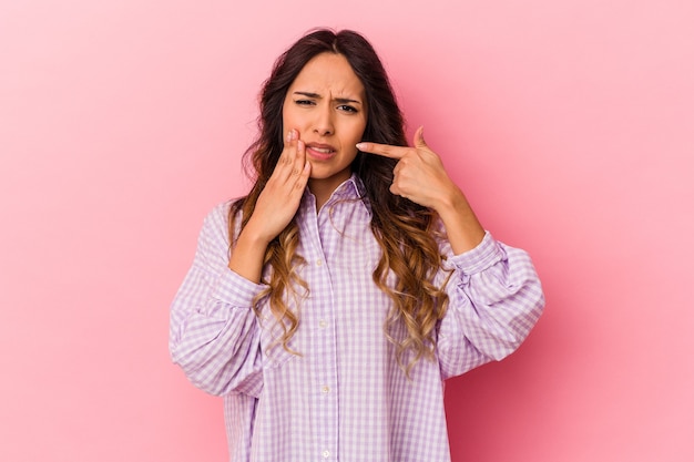 Foto giovane donna messicana isolata sulla parete rosa che ha un forte dolore ai denti, dolore molare.