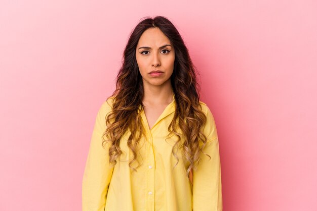 Young mexican woman isolated on pink wall sad, serious face, feeling miserable and displeased.