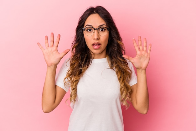 Young mexican woman isolated on pink wall screaming to the sky, looking up, frustrated.