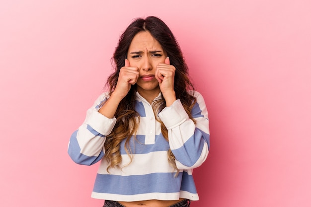 Young mexican woman isolated on pink wall whining and crying disconsolately.