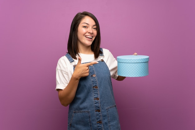 Young Mexican woman over isolated wall holding gift box