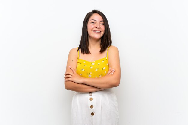 Young Mexican woman over isolated wall keeping the arms crossed in frontal position