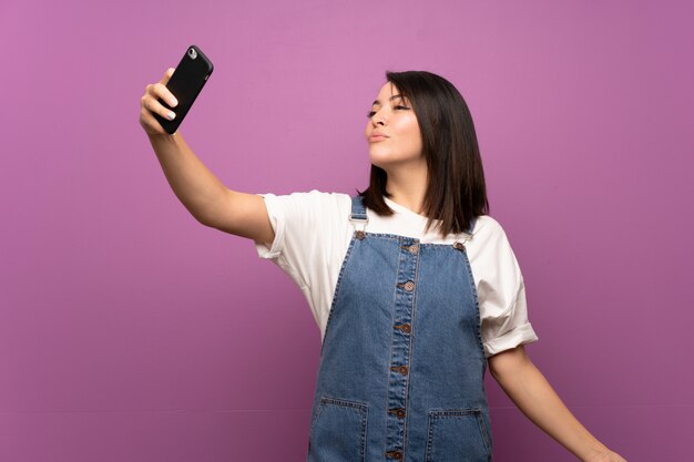 携帯電話でselfieを作る孤立した壁の上の若いメキシコ人女性